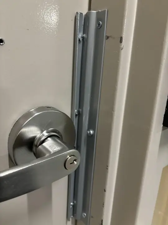 Lever handle lock with a metal guard plate on a commercial door