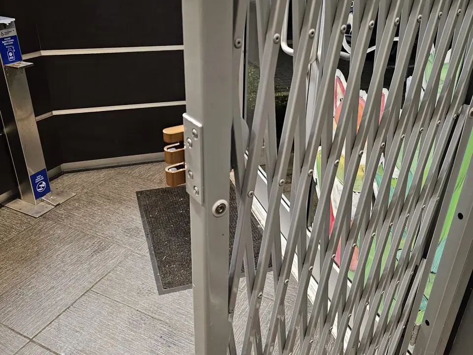 Folding security gate pulled across a building entrance beside a reception desk
