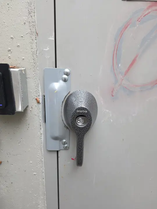Heavy-duty cylinder lock and strike plate on a steel door