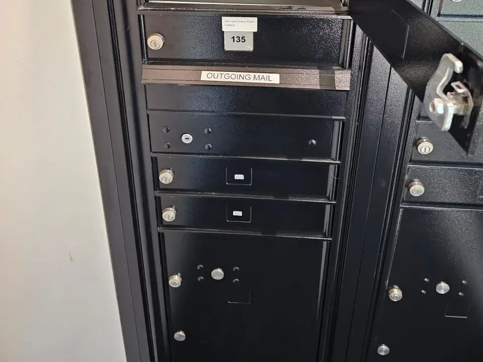 Black lock-box mailboxes with numbered compartments and an outgoing mail slot