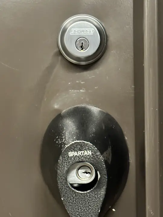 Front door with a deadbolt and a damaged lock cover