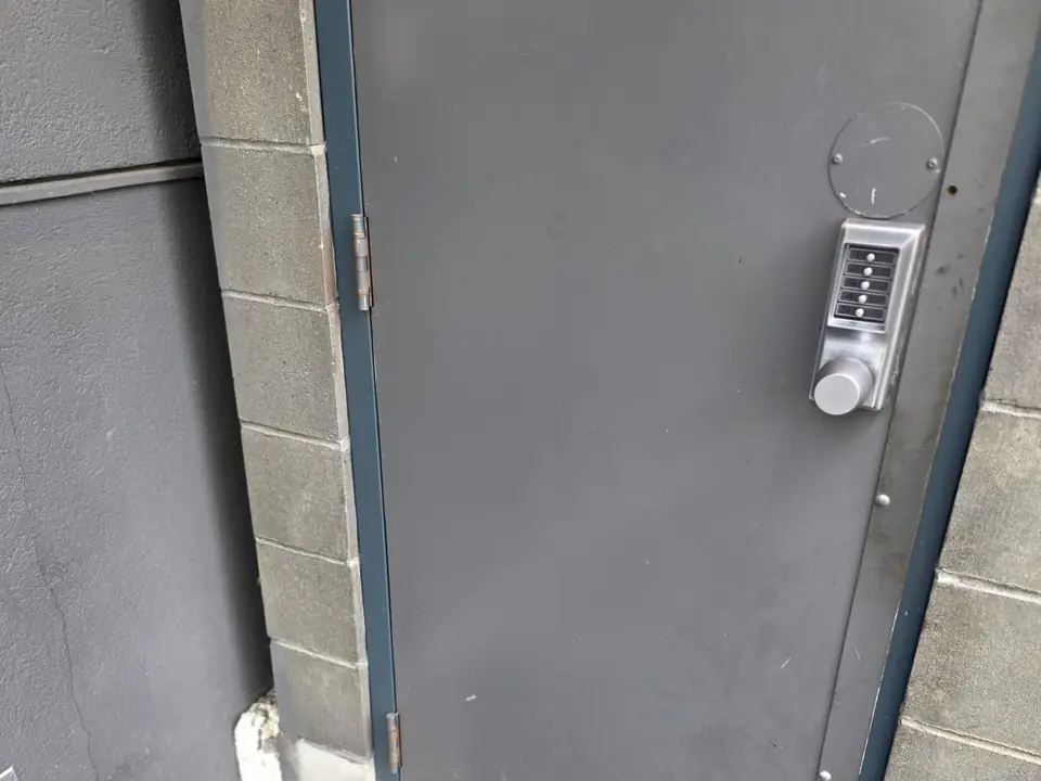 Keypad lock on a steel commercial door at the side of a building