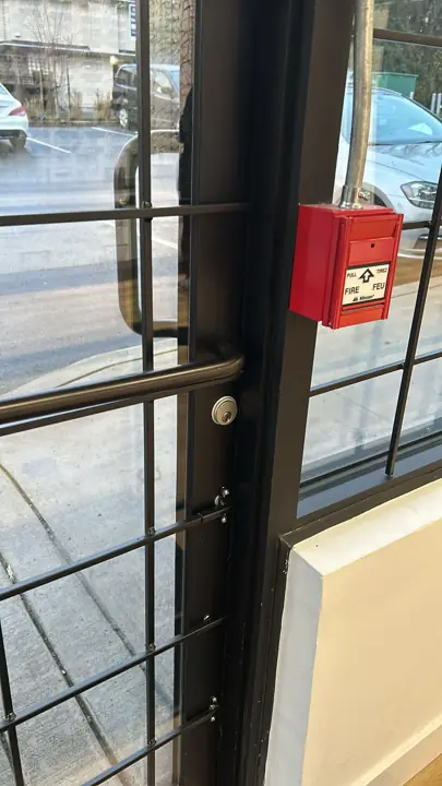 Glass door with a push bar and an emergency exit lock