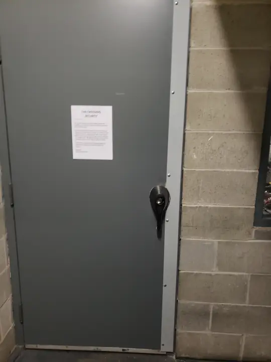 Grey steel door with a lever lock set into a brick wall