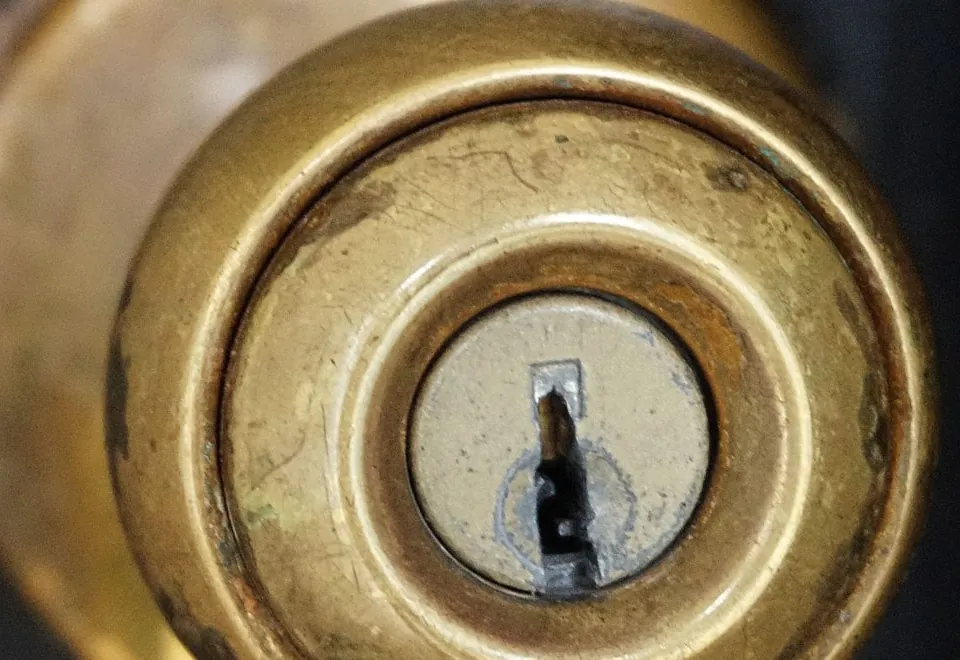 A worn brass door knob with a keyed cylinder, ready to be rekeyed