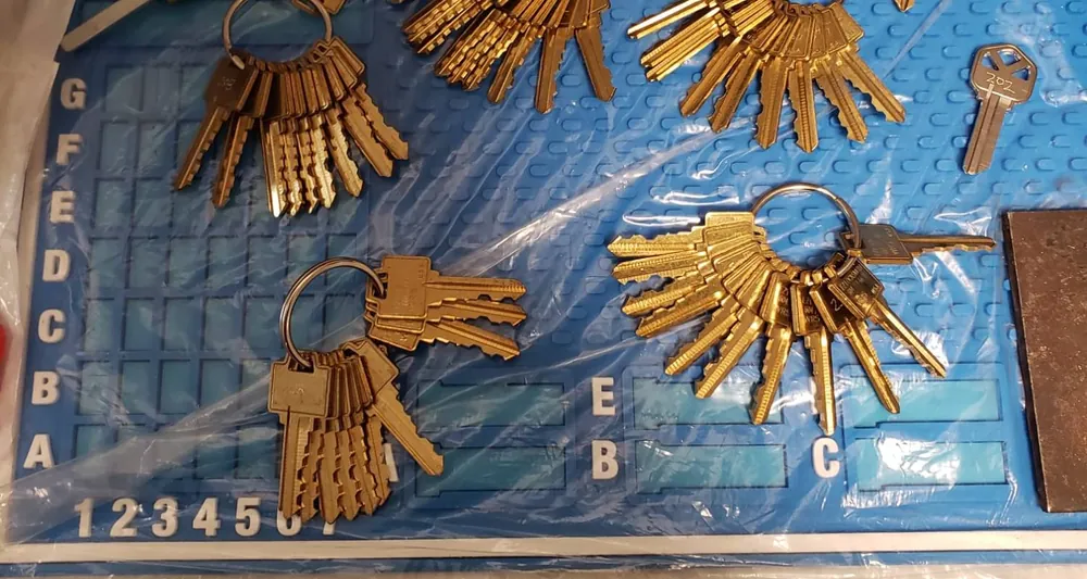 Sets of brass key blanks on rings laid out on a keying mat